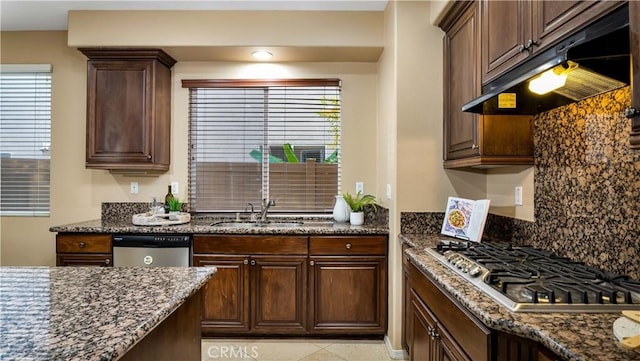 kitchen with light tile patterned floors, stainless steel appliances, dark stone countertops, and sink