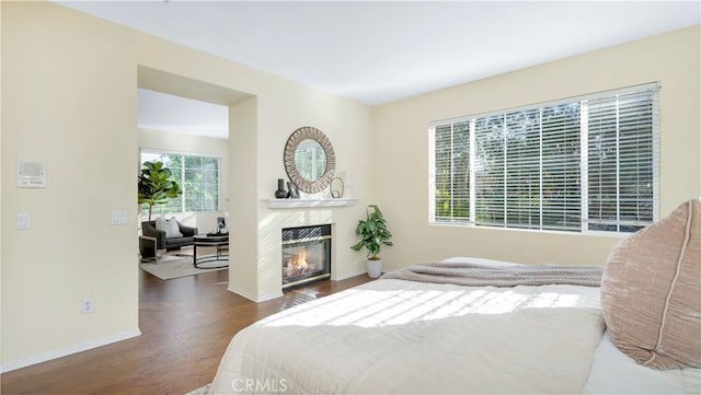 bedroom with a tile fireplace and dark wood-type flooring