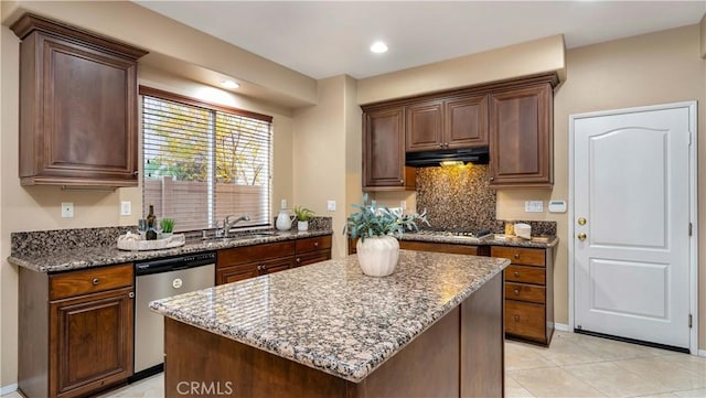 kitchen with stone counters, sink, stainless steel appliances, light tile patterned floors, and a kitchen island