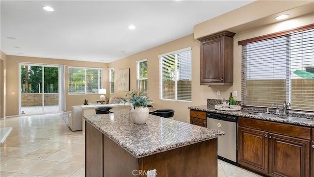 kitchen with light stone countertops, a healthy amount of sunlight, stainless steel dishwasher, and a kitchen island