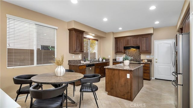 kitchen featuring light tile patterned floors, tasteful backsplash, stone countertops, a kitchen island, and stainless steel appliances