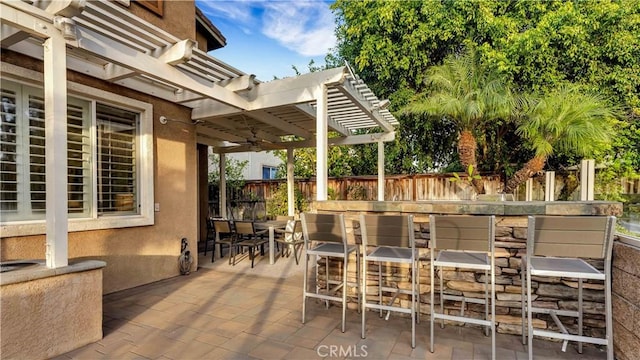 view of patio featuring a pergola, ceiling fan, and exterior bar