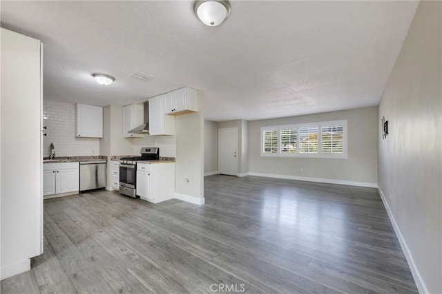 kitchen featuring white cabinets, appliances with stainless steel finishes, light wood-type flooring, and wall chimney range hood