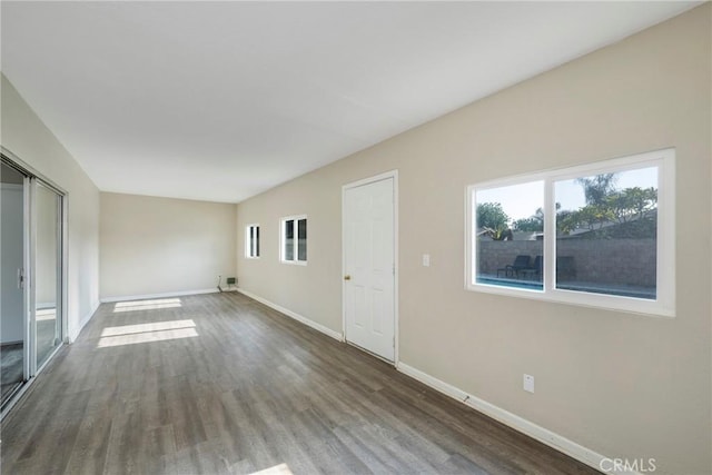 unfurnished room featuring a wealth of natural light and dark hardwood / wood-style floors