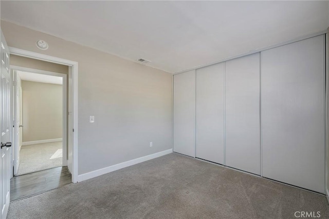 unfurnished bedroom featuring light colored carpet and a closet