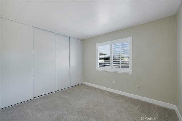 unfurnished bedroom with light carpet and a closet