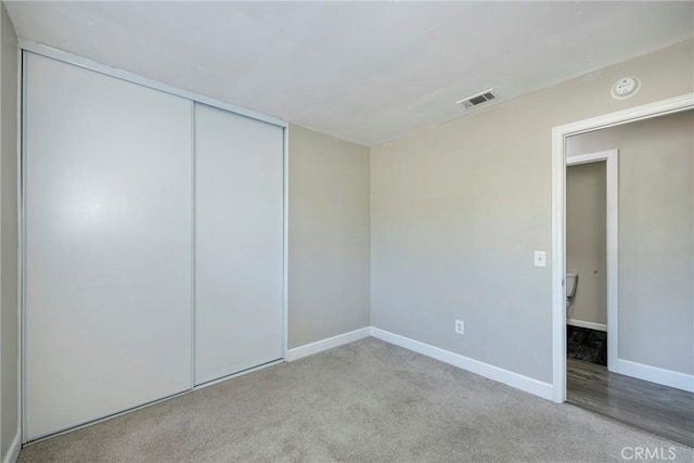 unfurnished bedroom featuring light carpet and a closet