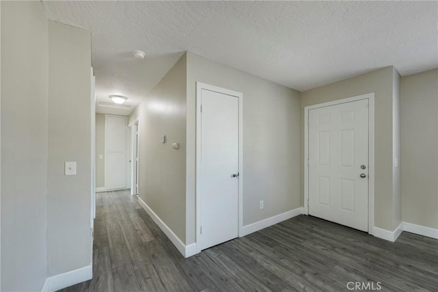 hall with a textured ceiling and dark wood-type flooring