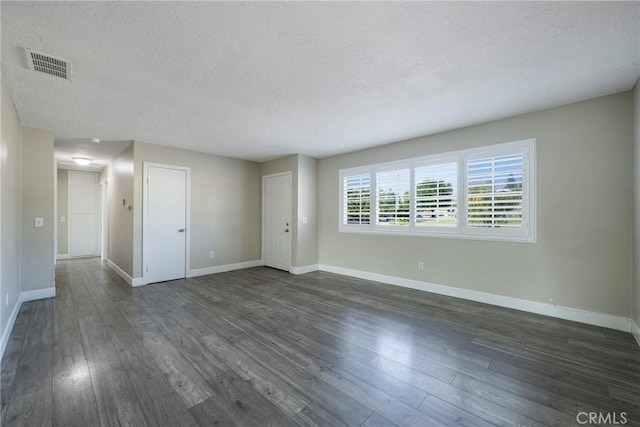 unfurnished room with a textured ceiling and dark hardwood / wood-style floors