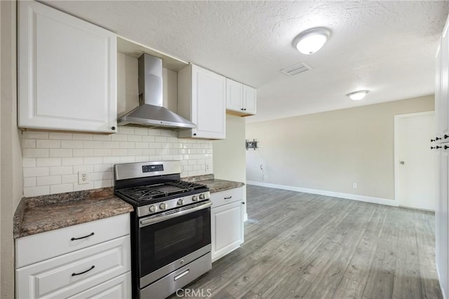 kitchen featuring white cabinets, stainless steel gas stove, hardwood / wood-style flooring, and wall chimney range hood