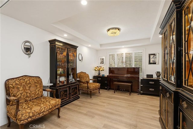 sitting room with light hardwood / wood-style floors and a raised ceiling