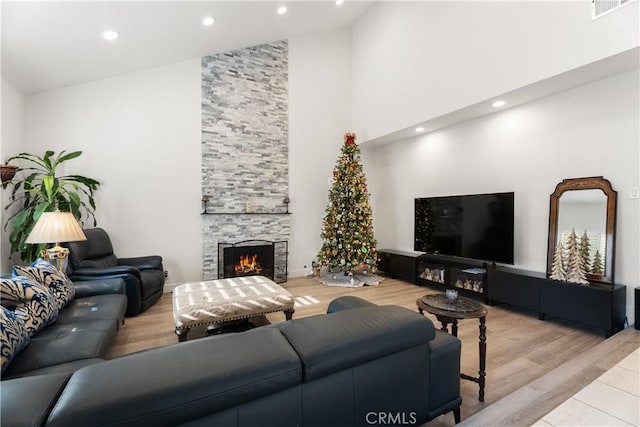 living room with high vaulted ceiling, light wood-type flooring, and a fireplace