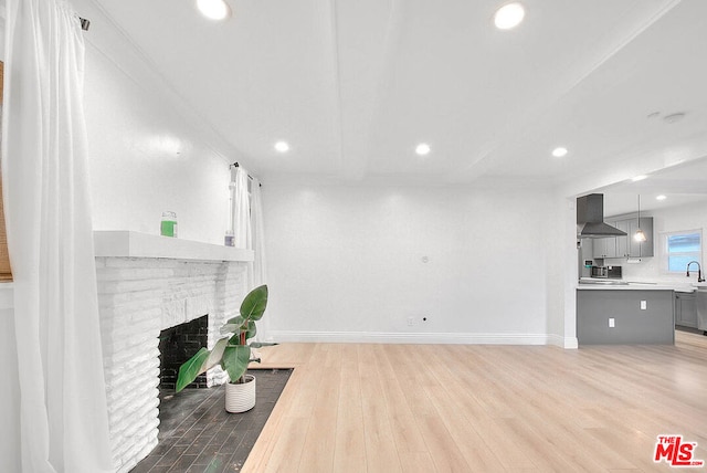 living room featuring crown molding, a fireplace, wood-type flooring, and sink