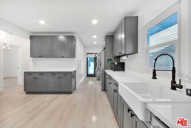 kitchen with gray cabinetry, sink, a healthy amount of sunlight, and light hardwood / wood-style floors