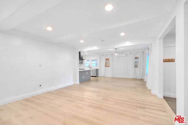 unfurnished living room featuring beam ceiling, sink, and light hardwood / wood-style flooring