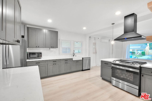 kitchen with island range hood, plenty of natural light, light hardwood / wood-style flooring, and appliances with stainless steel finishes