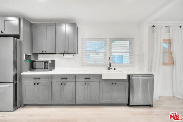 kitchen featuring tasteful backsplash, gray cabinets, sink, and appliances with stainless steel finishes