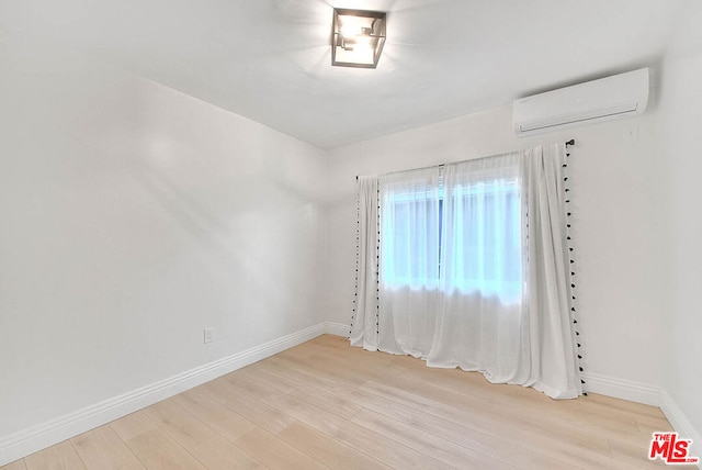 spare room featuring light hardwood / wood-style floors and a wall unit AC