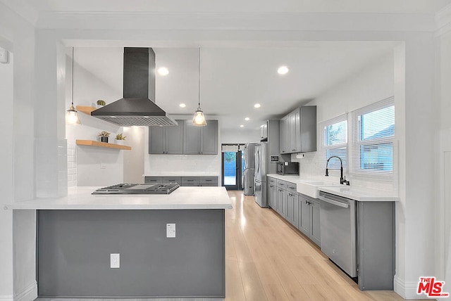 kitchen featuring hanging light fixtures, range hood, light hardwood / wood-style floors, kitchen peninsula, and stainless steel appliances