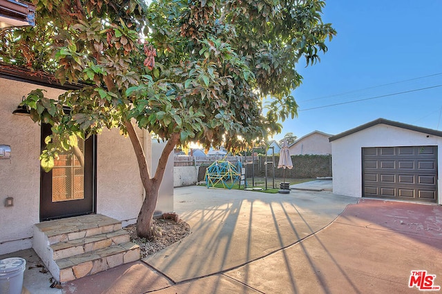 view of patio / terrace featuring a garage and an outbuilding