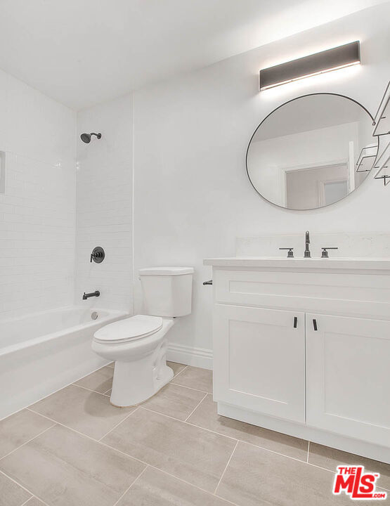 full bathroom featuring tile patterned floors, vanity, toilet, and tiled shower / bath