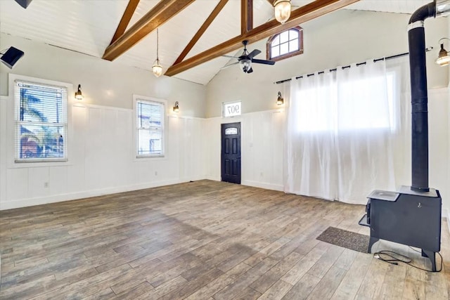 living room featuring a wood stove, high vaulted ceiling, ceiling fan, beamed ceiling, and wood-type flooring