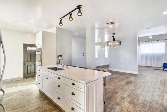 kitchen with stainless steel double oven, sink, white cabinets, dark hardwood / wood-style floors, and a kitchen island