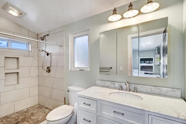 bathroom featuring a tile shower, plenty of natural light, vanity, and toilet