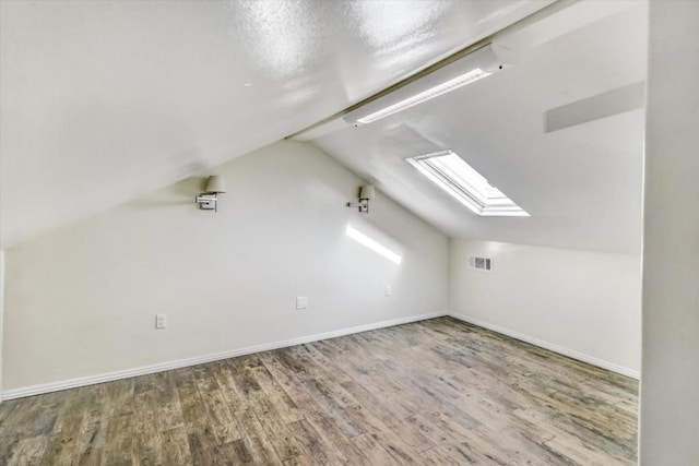 bonus room with vaulted ceiling with skylight and wood-type flooring