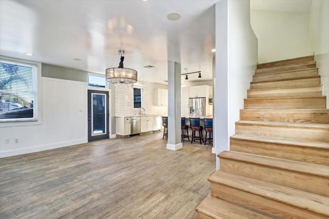 interior space with sink, rail lighting, wood-type flooring, and an inviting chandelier