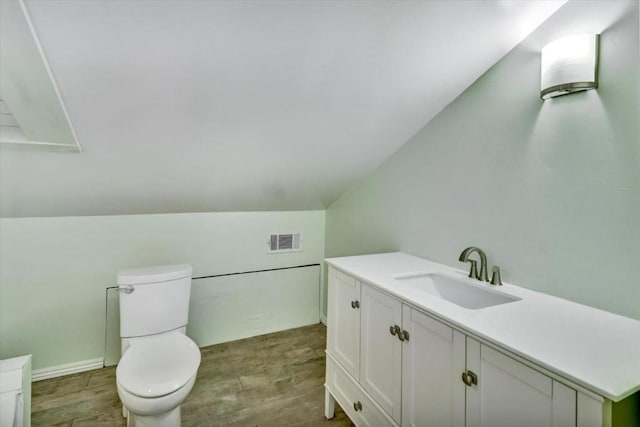 bathroom featuring vanity, hardwood / wood-style flooring, toilet, and lofted ceiling