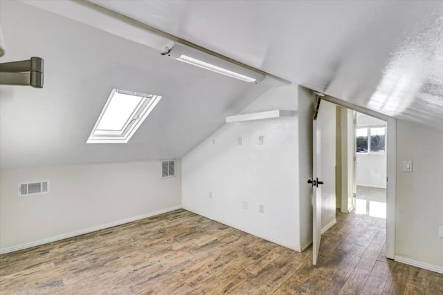 bonus room with dark hardwood / wood-style flooring and lofted ceiling with skylight