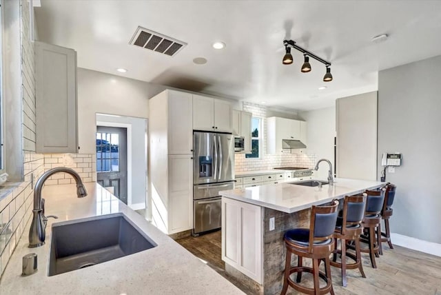 kitchen with decorative backsplash, stainless steel appliances, white cabinetry, and sink