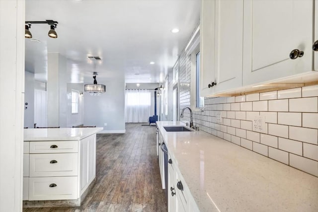 kitchen featuring dark hardwood / wood-style floors, light stone countertops, white cabinetry, and sink