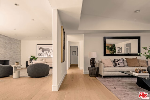 living room featuring a fireplace, light hardwood / wood-style floors, and vaulted ceiling