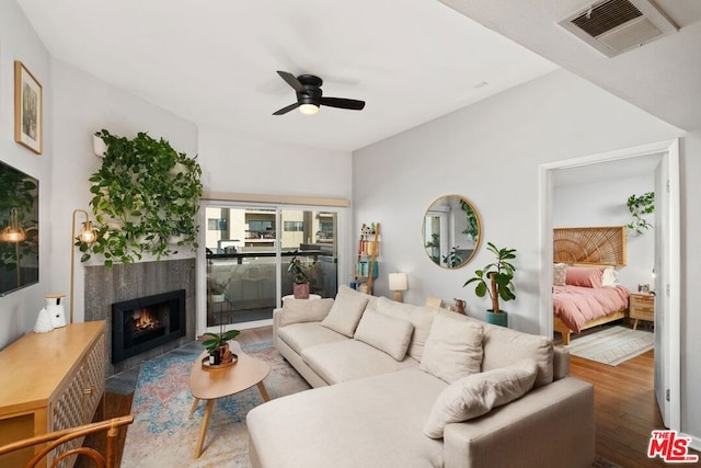 living room featuring a tile fireplace, ceiling fan, and dark hardwood / wood-style floors