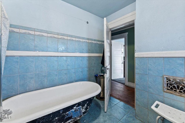 bathroom with a tub, tile patterned flooring, and tile walls