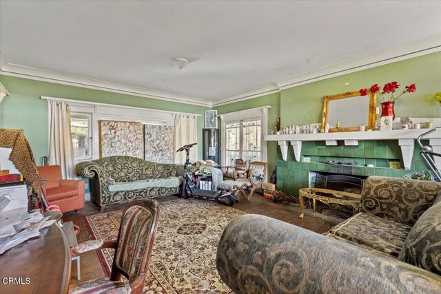 interior space with hardwood / wood-style floors, ornamental molding, a healthy amount of sunlight, and a tiled fireplace