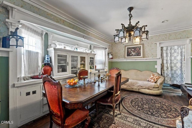 dining room featuring wood-type flooring, crown molding, and an inviting chandelier