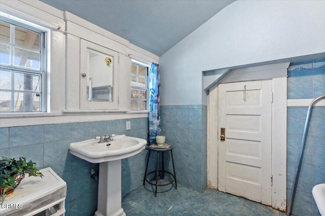 bathroom with tile patterned floors, tile walls, sink, and vaulted ceiling