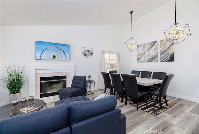 living room featuring light hardwood / wood-style floors, high vaulted ceiling, and a tiled fireplace