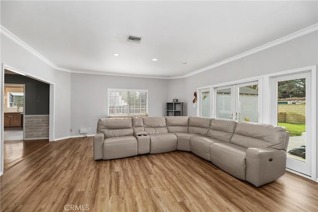 living room with crown molding, a wealth of natural light, and light hardwood / wood-style flooring