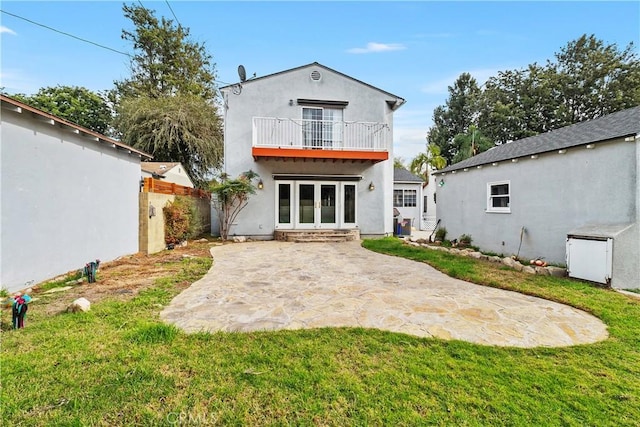 rear view of property with a lawn, a balcony, a patio, and french doors