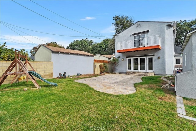 back of house with a lawn, french doors, a playground, a balcony, and a patio