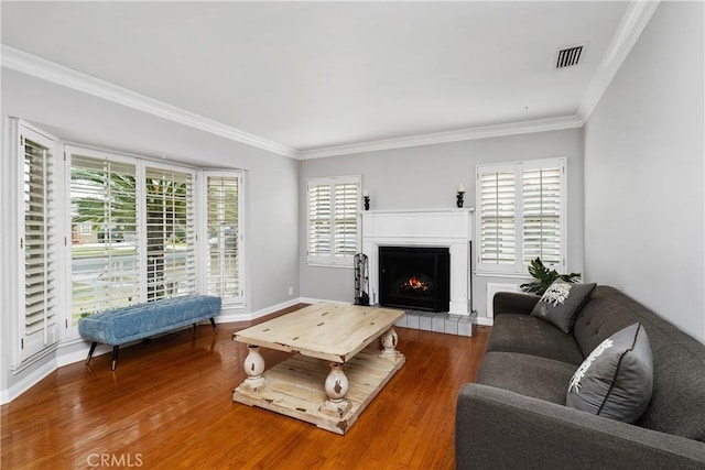 living room featuring a fireplace, hardwood / wood-style flooring, and crown molding