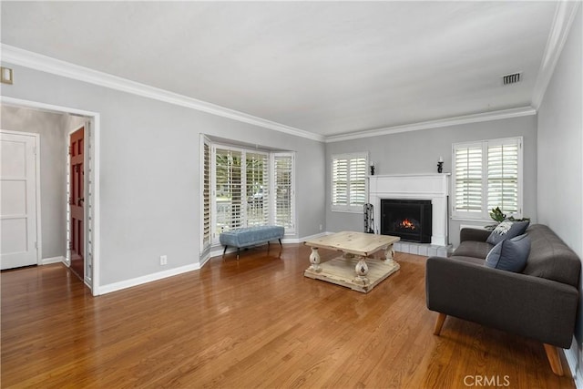 living room featuring hardwood / wood-style floors, crown molding, and a tiled fireplace