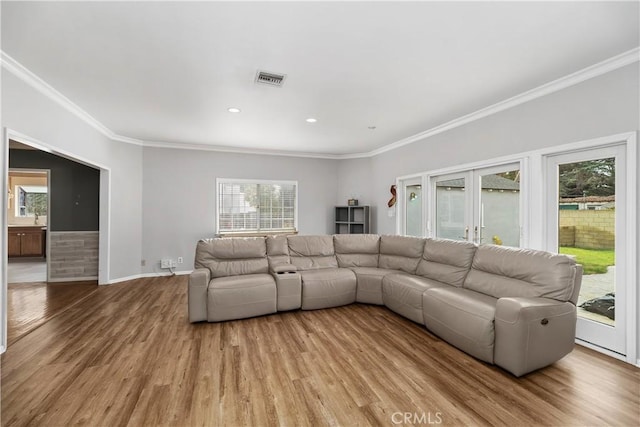 living room featuring light wood-type flooring, crown molding, and a healthy amount of sunlight