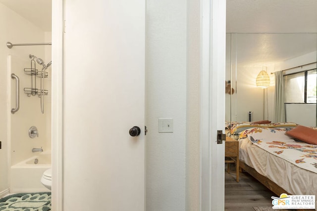 bathroom with shower / washtub combination, hardwood / wood-style floors, and toilet