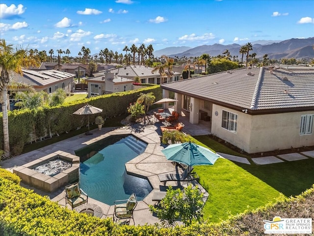 exterior space with a mountain view, a patio, a fire pit, and a lawn