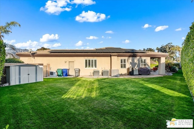 back of property featuring solar panels, a shed, a yard, central AC, and a patio